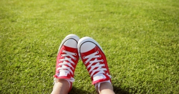 Primo piano di piedi di un adolescente sdraiato su un prato