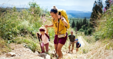 bambina in montagna sale sentiero con mamma